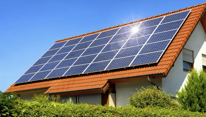 Panneaux solaires sur un toit de tuiles rouges, capturant le soleil. Un potentiel solaire toiture prometteur pour cette maison.
