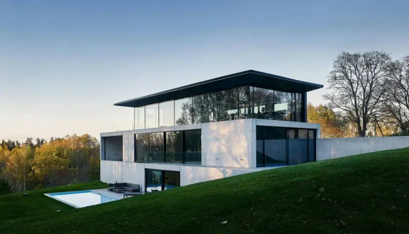 Une maison positive aux lignes épurées, avec une piscine et une vue sur la forêt.