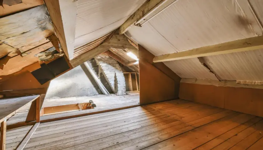 Espace brut sous les toits, idéal pour un projet de comment aménager des combles. Planchers en bois, poutres apparentes et murs en briques.