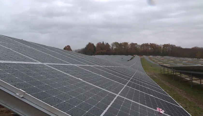 Vaste étendue de panneaux solaires sous un ciel couvert, témoignant d'un projet photovoltaïque en Nouvelle-Aquitaine.