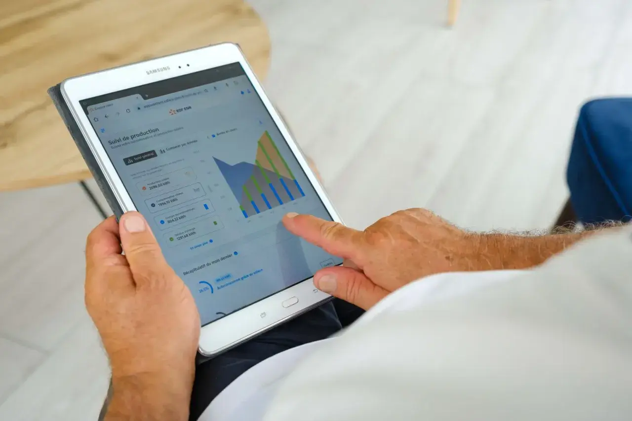 Un homme consulte sur sa tablette le suivi de sa production solaire EDF ENR, vérifiant le délai signature contrat EDF OA.