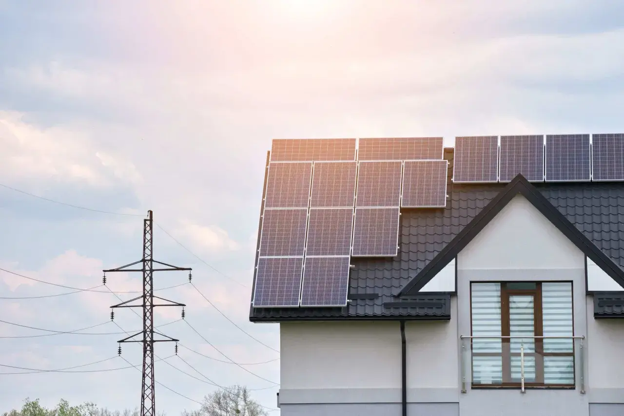Le calepinage panneau solaire sur le toit d'une maison moderne, avec un pylône électrique en arrière-plan.