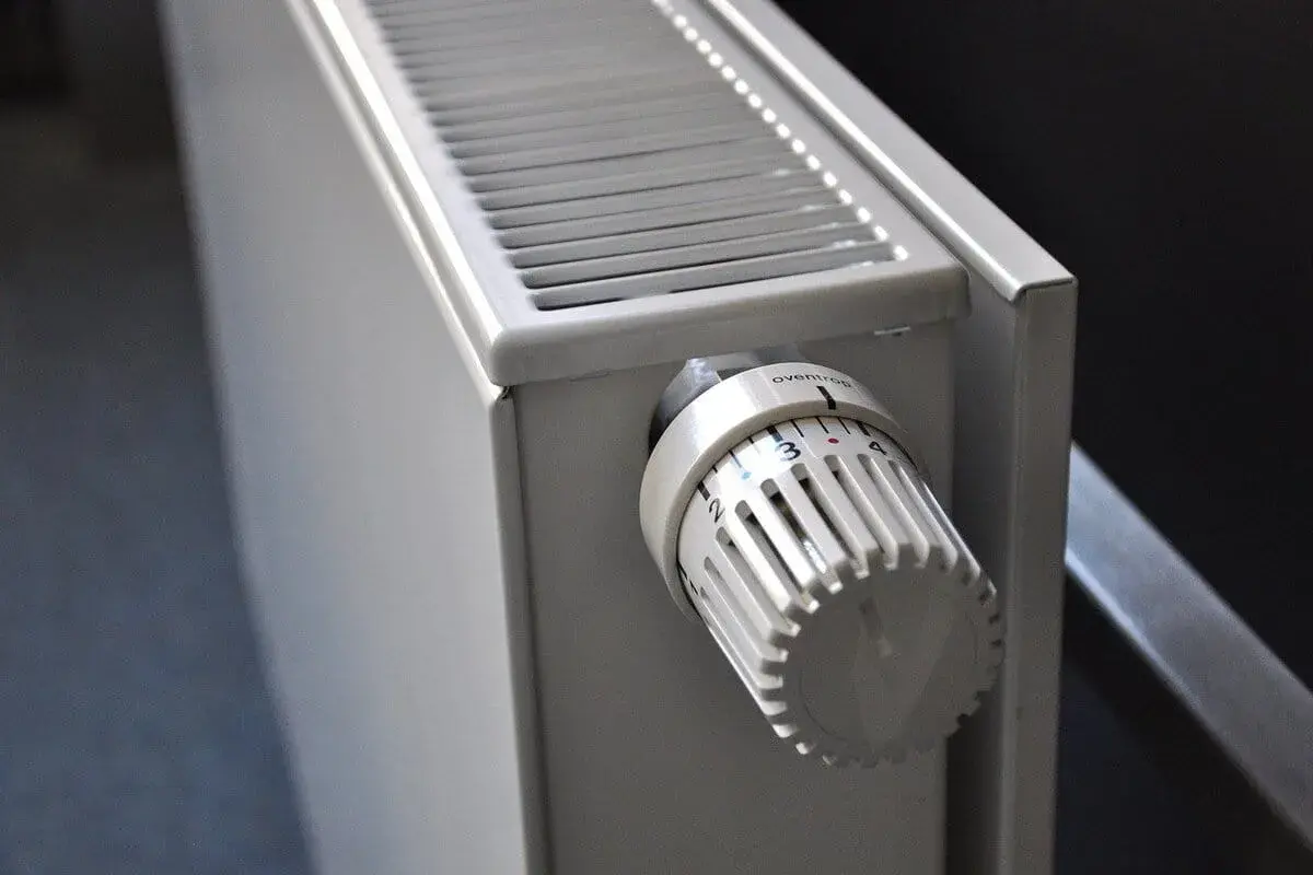 Gros plan sur un radiateur blanc, élément clé d'une installation de chauffage central, avec sa molette de réglage de température.