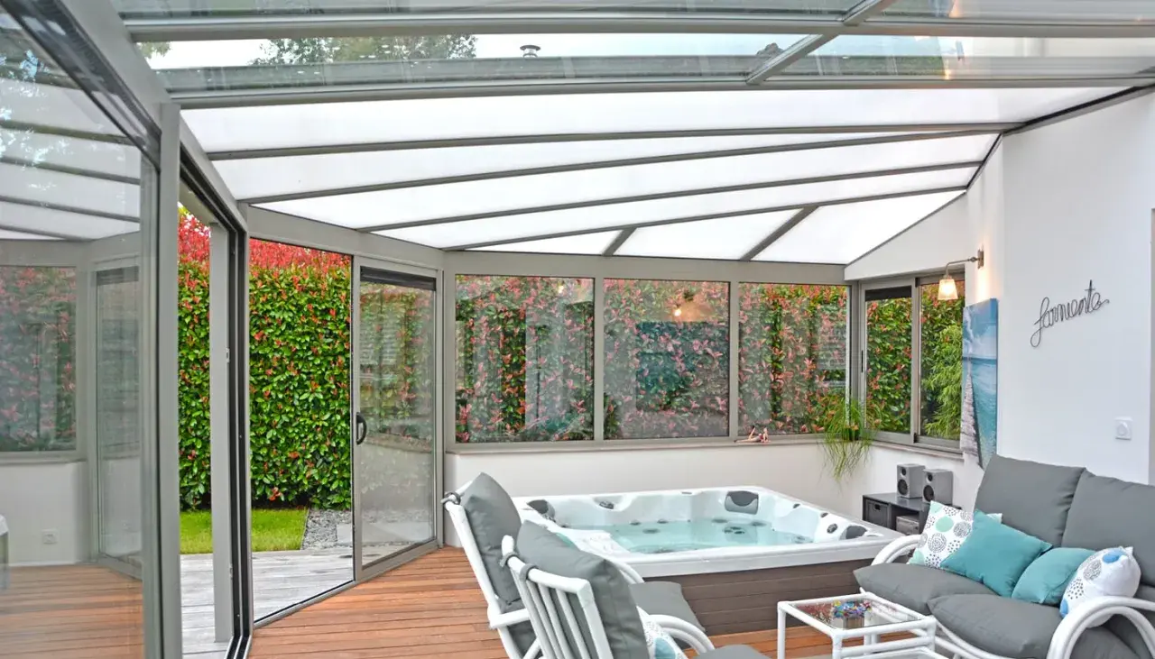 Veranda avec jacuzzi et salon, profitant d'une isolation toiture veranda par l'interieur pour un confort optimal toute l'année.