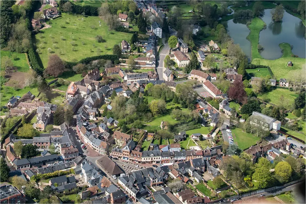 Vue aérienne d'un village pittoresque, un schéma directeur immobilier exemple, avec ses maisons aux toits de tuiles, ses rues sinueuses et son étang.