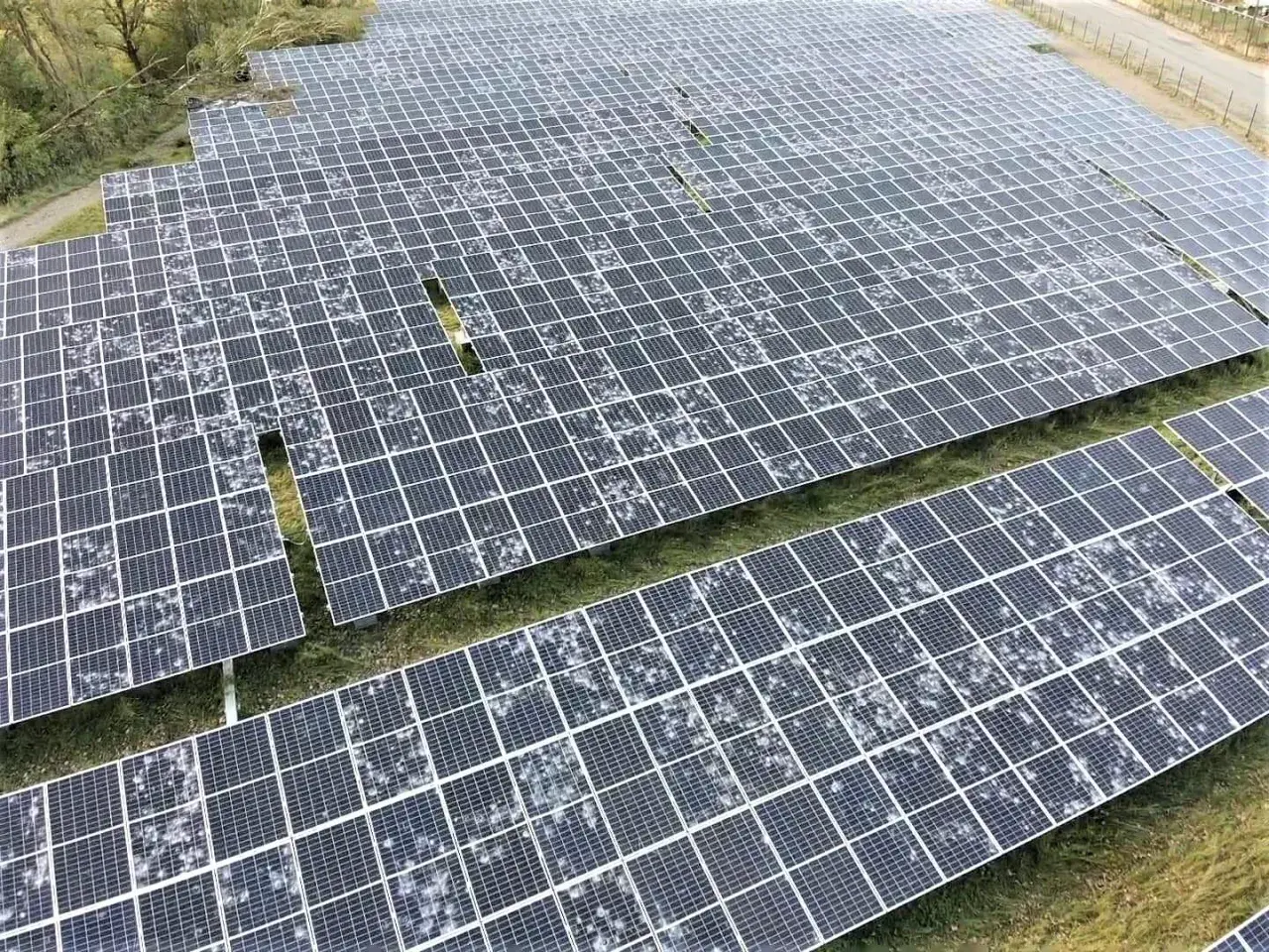 Champ de panneaux solaires recouverts de grêle, montrant la résilience de l'énergie renouvelable face aux intempéries.