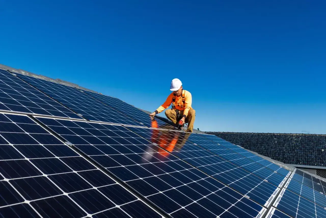 Un technicien installe des panneaux solaires sur un toit, une étape clé pour l'autoconsommation sans déclaration Enedis.