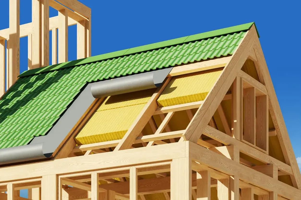 Structure en bois d'une maison avec toiture verte et isolation par l'extérieur jaune visible.