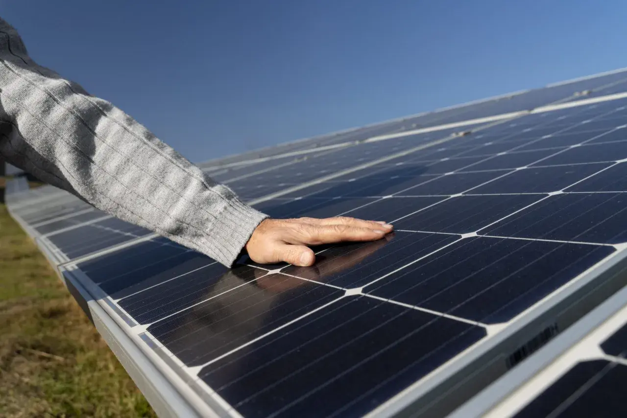 Main posée sur des panneaux photovoltaïques, vérifiant la température sous le soleil.