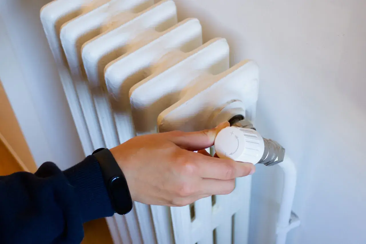 Main tenant ajuste le thermostat d'un radiateur qui fait du bruit, espérant trouver le silence.