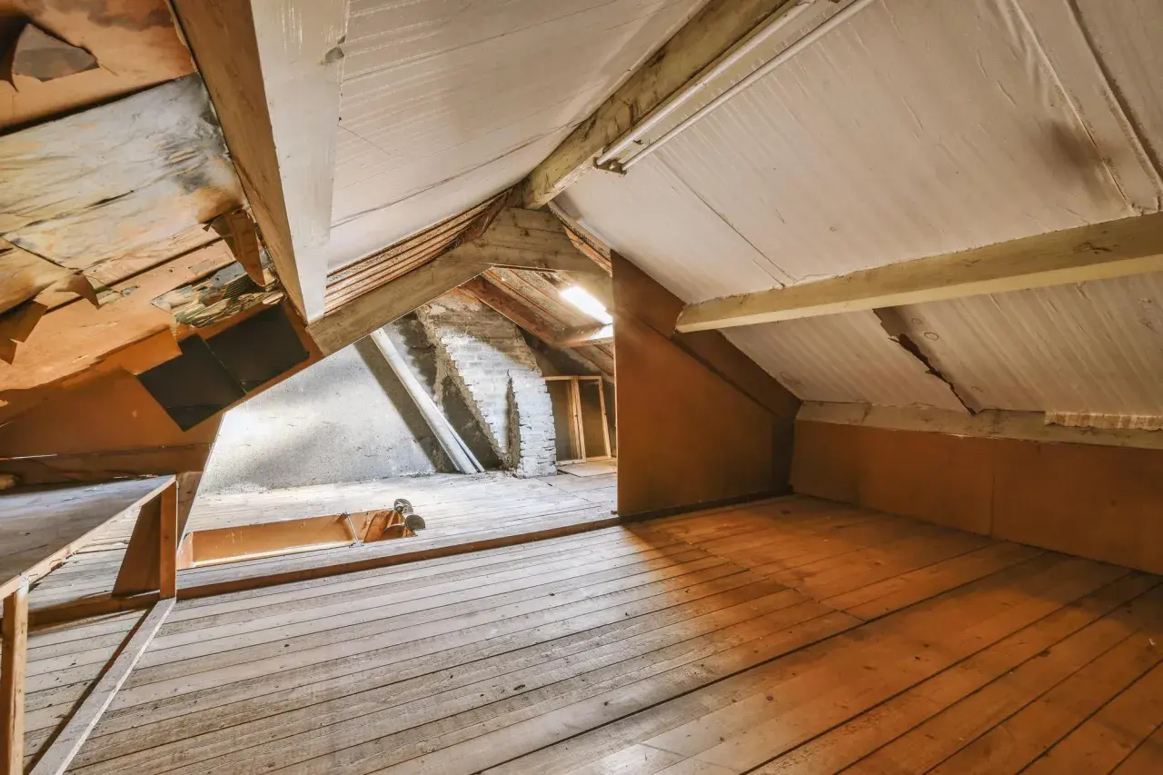 Espace brut sous les toits, idéal pour un projet de comment aménager des combles. Planchers en bois, poutres apparentes et murs en briques.