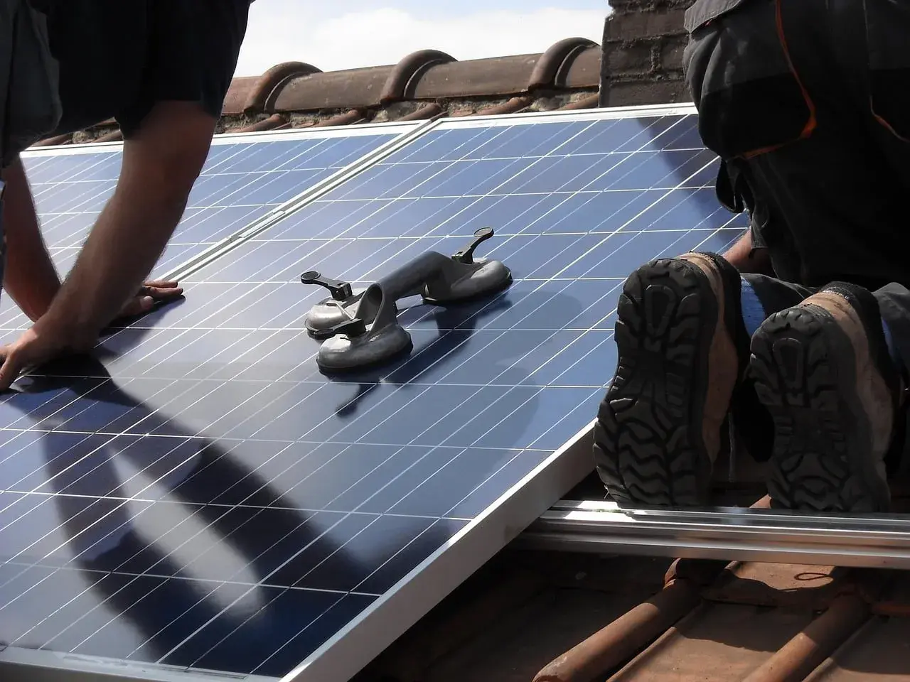 Un installateur panneau solaire agréé manipule un panneau sur un toit. Des ventouses sont prêtes à aider.