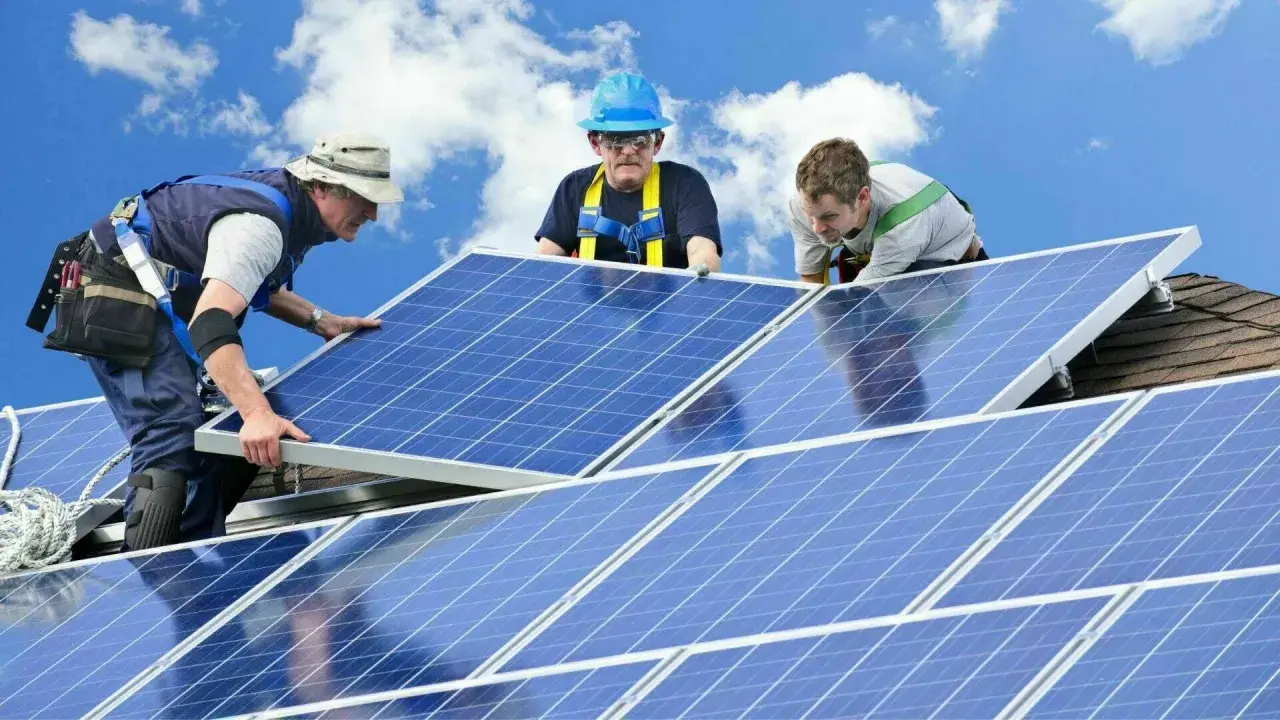 Trois techniciens installent des panneaux solaires sur un toit. Une installation sûre et pérenne, gage d'une **assurance décennale photovoltaïque** fiable.