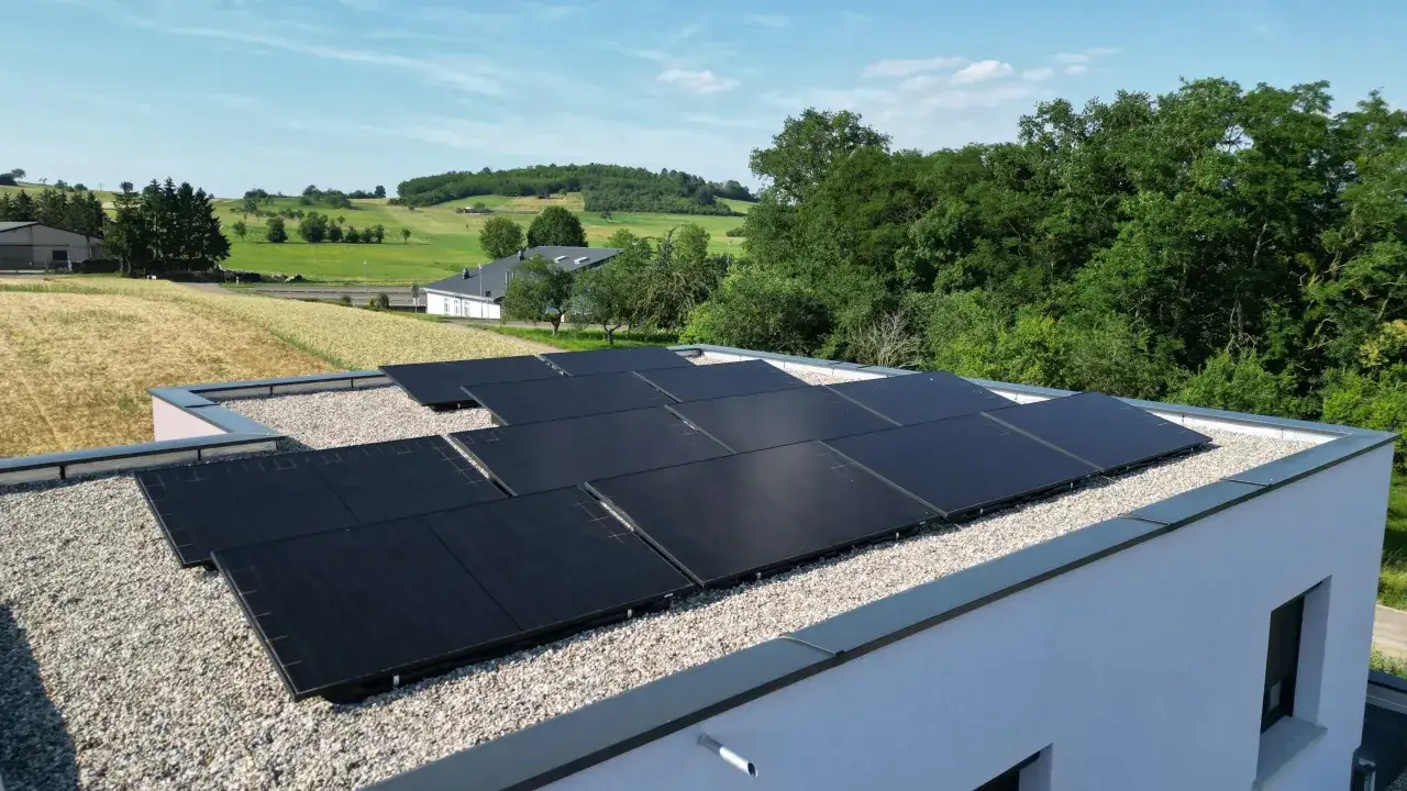 Panneaux solaires sur un toit plat, garantissant une assurance d&eacute;cennale photovolta&iuml;que pour cette installation moderne dans un paysage verdoyant.