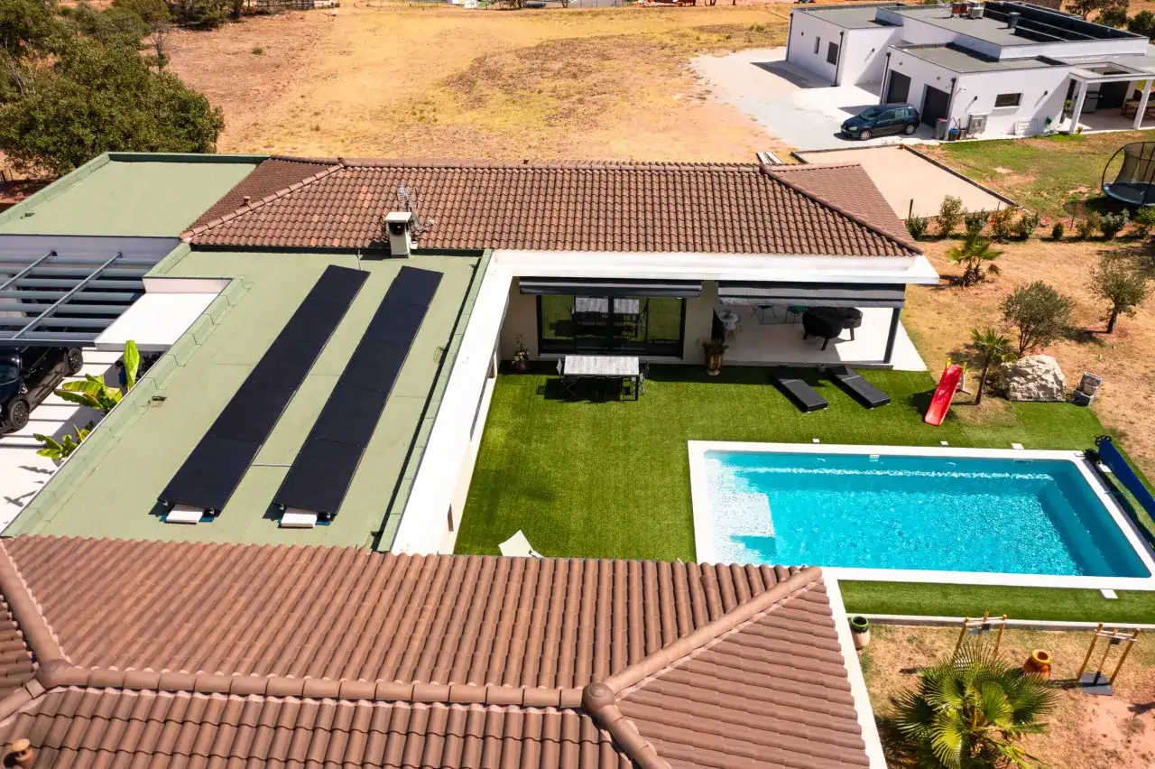 Vue aérienne d'une maison moderne avec piscine et tva panneaux photovoltaïques sur le toit plat.