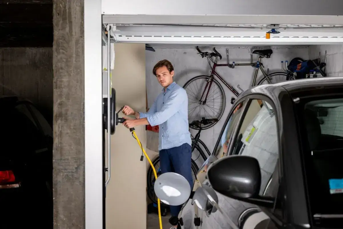 Un homme branche sa voiture &eacute;lectrique &agrave; une borne de recharge. La loi LOM encourage l'installation de bornes de recharge pour les v&eacute;hicules propres.