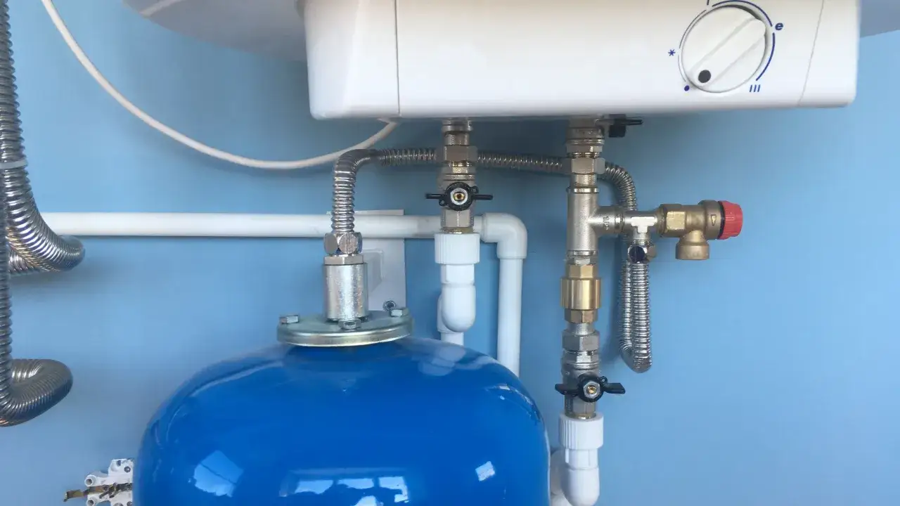 Détail des tuyaux et vannes d'un chauffe-eau, prêt pour un remplacement.