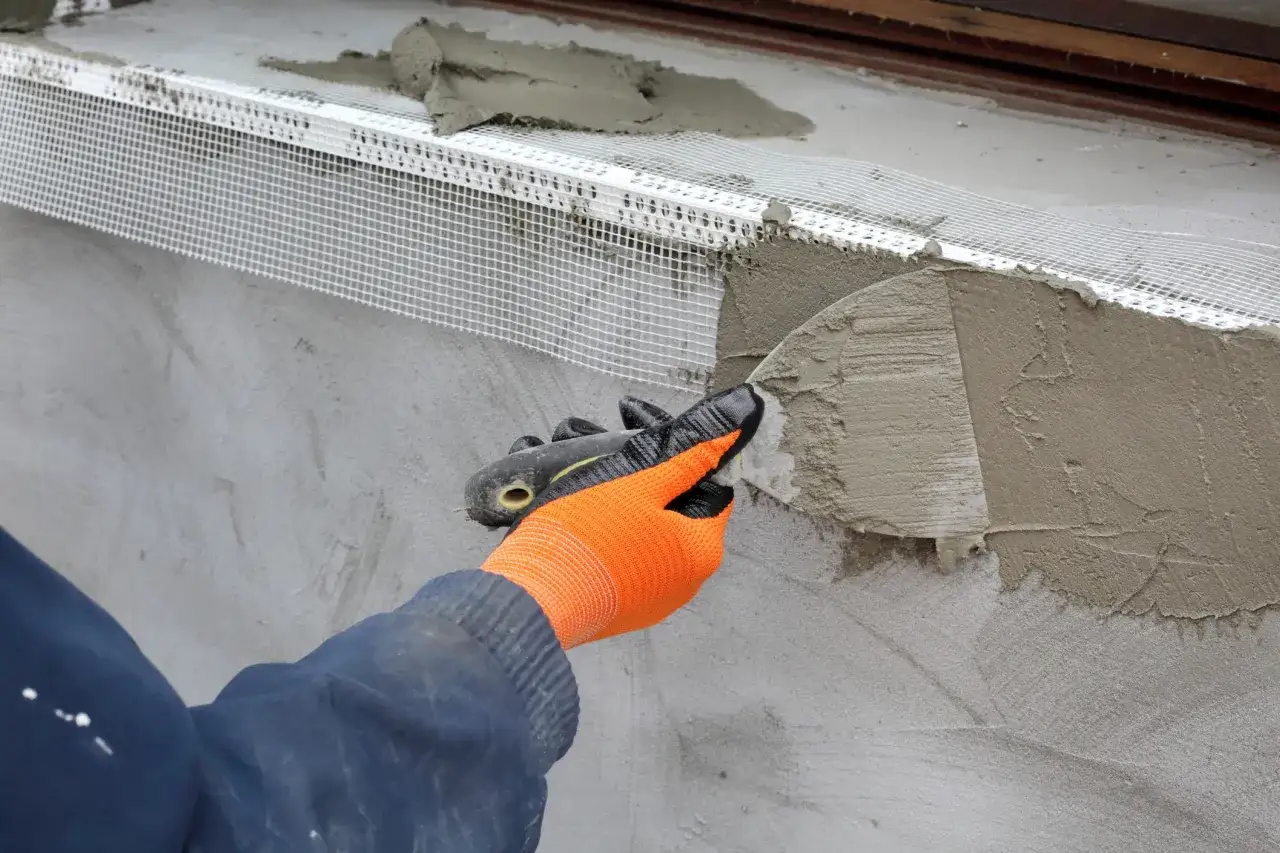 Application d'un enduit isolant extérieur avec une truelle, renforçant la façade.