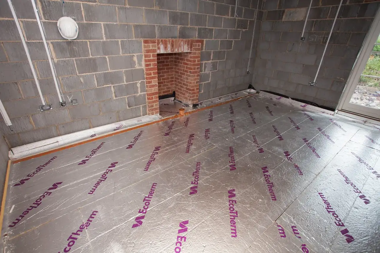 Pose de polystyrène extrudé au sol, prêt pour l'isolation. Le matériau argenté avec le logo EcoTherm couvre la surface.