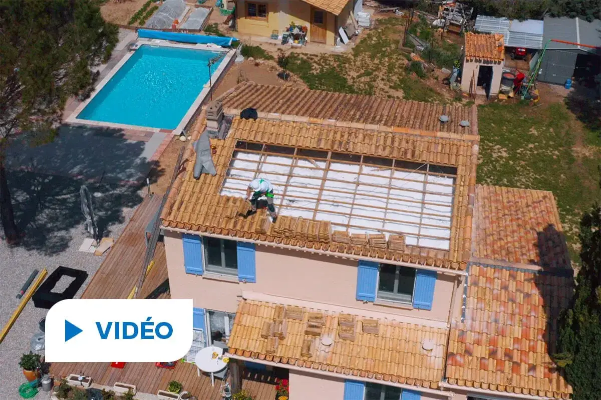 Un ouvrier travaille sur un toit pour l'installation de panneaux solaires, avec une piscine à proximité.