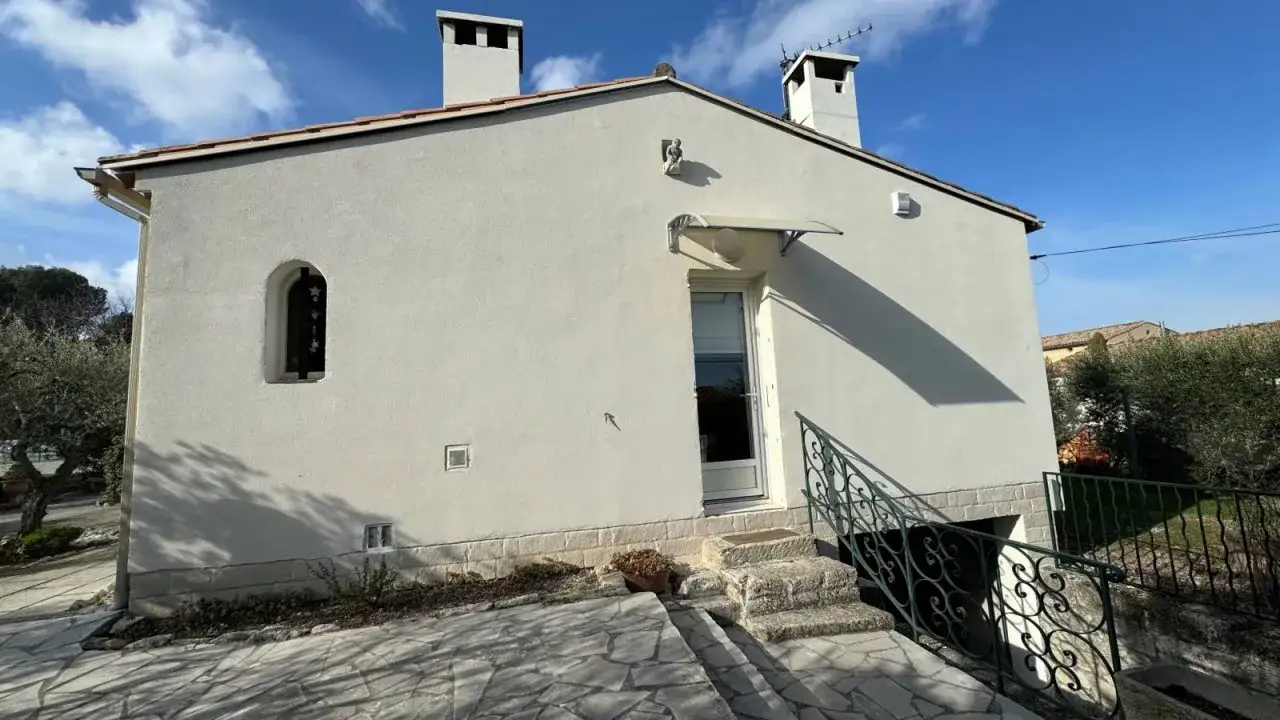 Fa&ccedil;ade d'une maison ph&eacute;nix 1970 avec chemin&eacute;es, fen&ecirc;tre cintr&eacute;e et escalier en pierre.