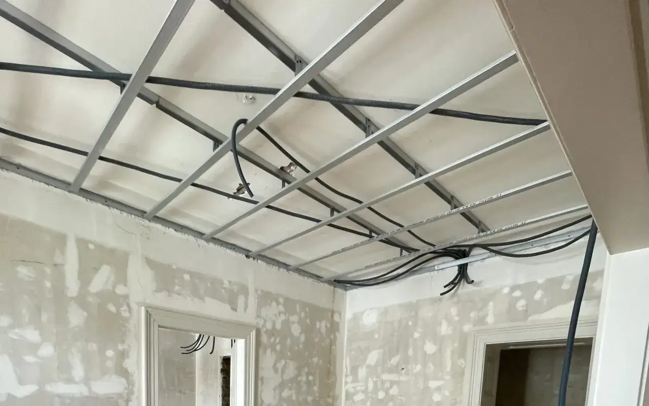 Structure métallique pour faux plafond d'un appartement en rénovation, avec câblage apparent. L'isolation plafond est en cours.